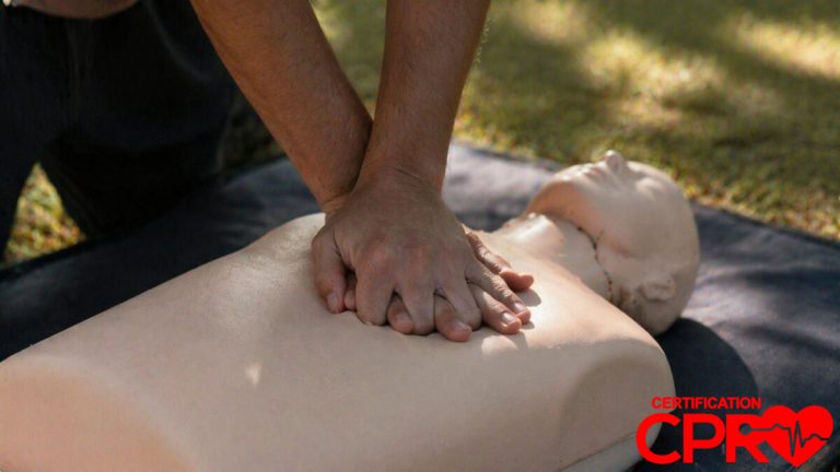 Person performing hands-only CPR on a mannequin outdoors in Denver.
